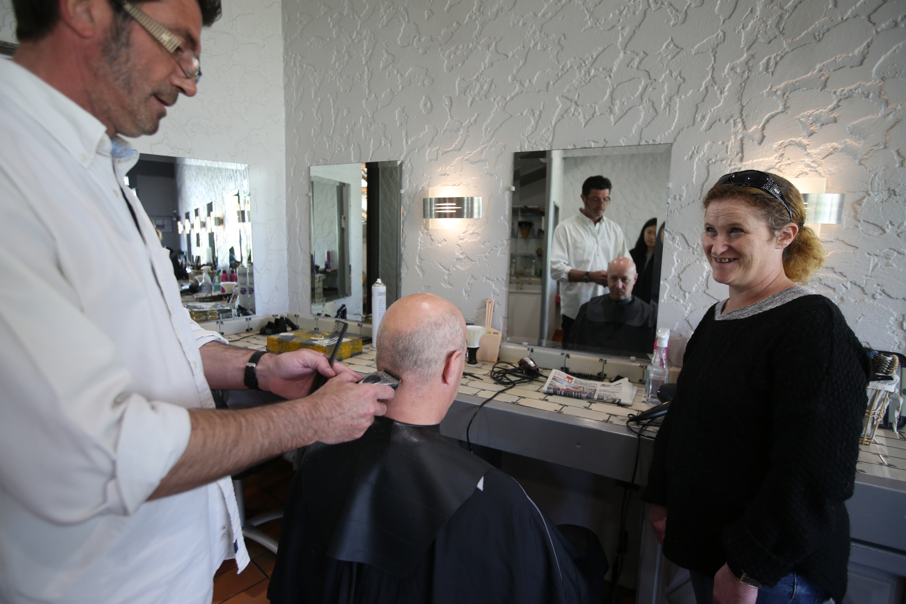 Femme montrant à un homme comment exercer le métier de coiffeur.