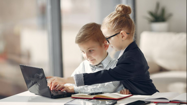 Deux enfants s'aidant face à un ordinateur