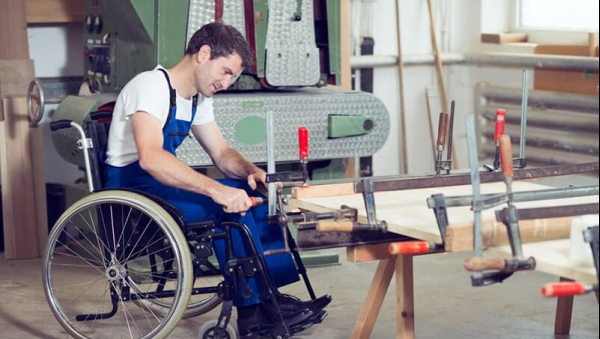 Homme en fauteuil roulant travaillant dans un atelier.