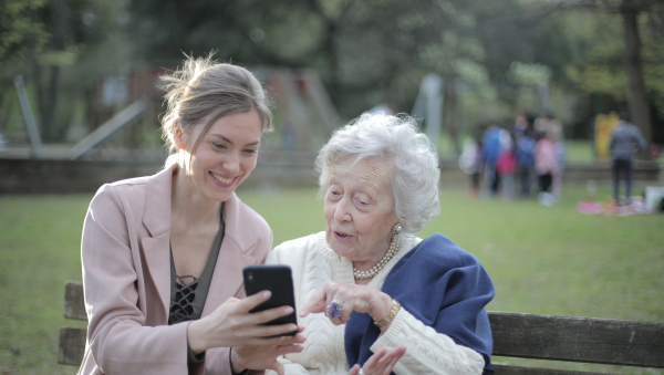 Femme aidant une personne âgée sur son téléphone